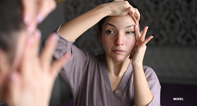 young woman performing face yoga cheek exercise