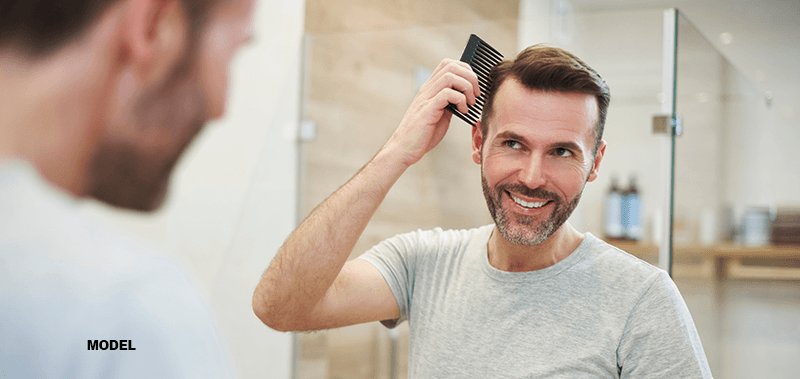 man combing hair after hair transplant