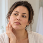 thumbnail woman examining facial puffiness in the mirror